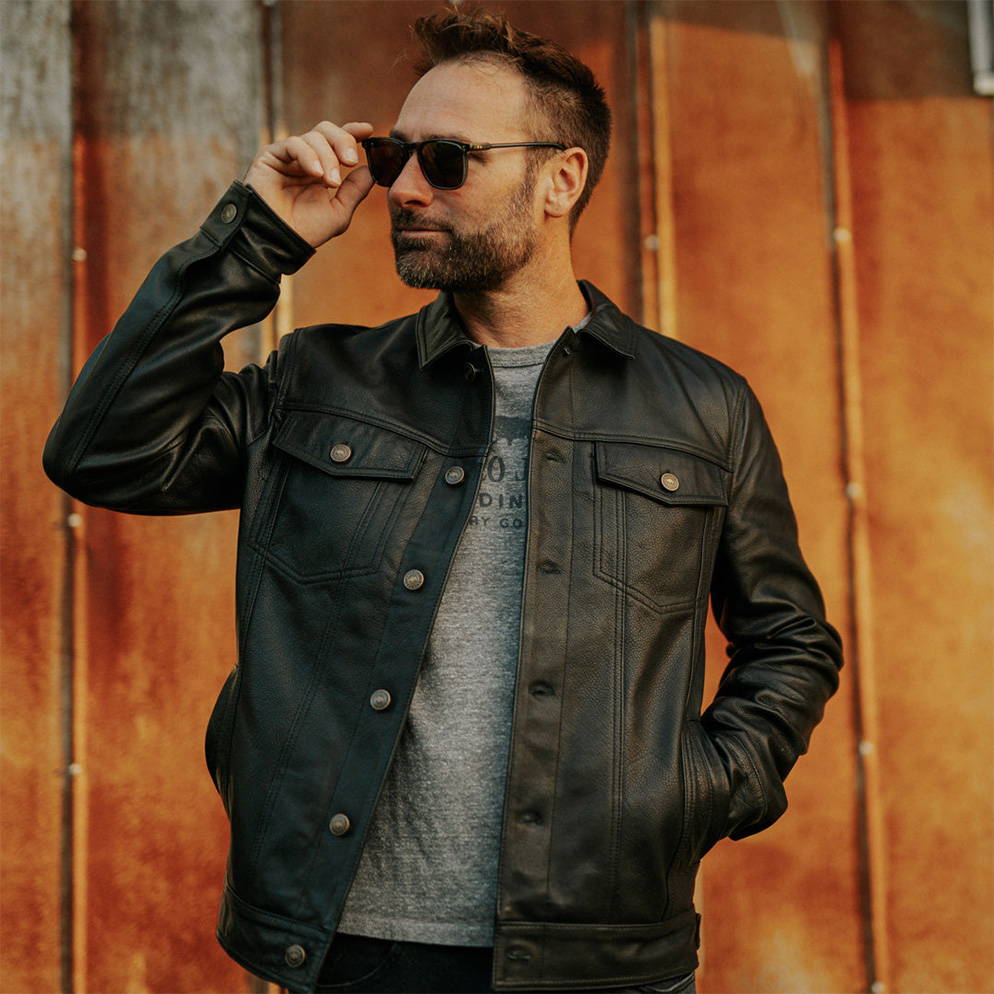 man with leather jacket in gray graphic tee shirt and black sunglasses